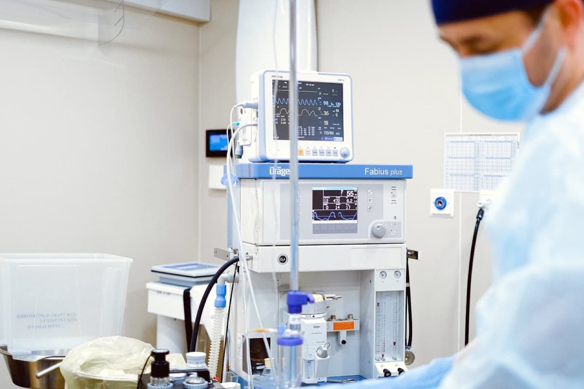 Anästhesist am Dräger-Narkosegerät mit Patientenmonitor im OP