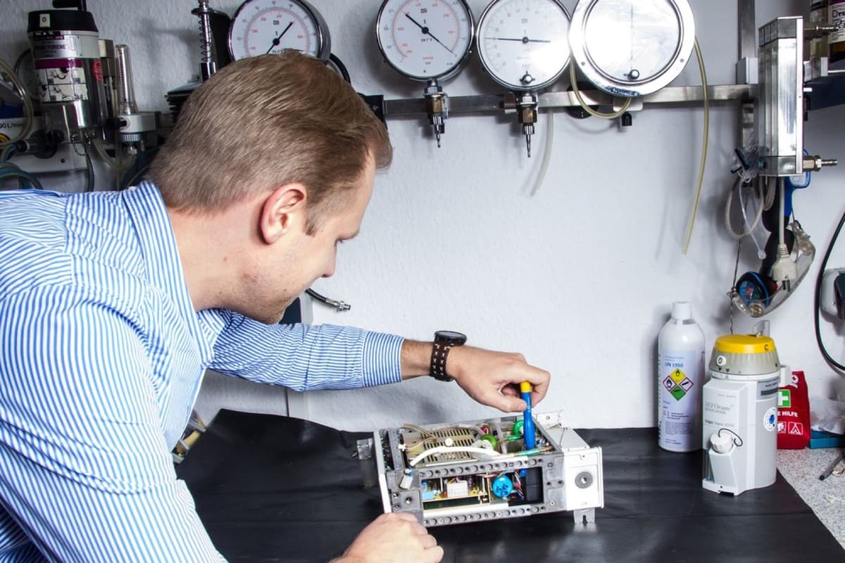 Techniker an der BelaMed-Werkbank mit Prüfmanometern und geöffnetem Gerät
